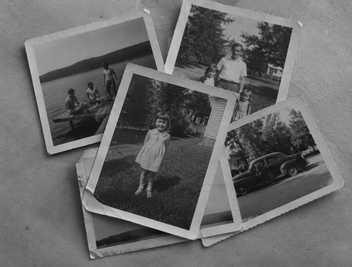 Old family snapshots scattered on a plain paper surface